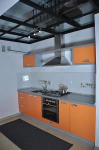 a kitchen with orange cabinets and a stove at Apartament Serce Miasta | The Heart of the City in Suwałki