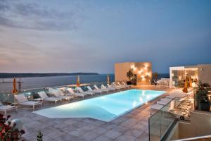 a swimming pool with lounge chairs and the ocean at Luna Holiday Complex in Mellieħa