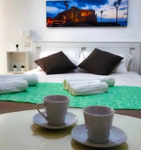 ナポリにあるMellos B&Bのベッドルーム1室(テーブルにカップ2つが付いたベッド1台付)
