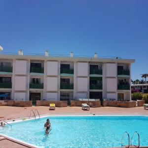 a person in a swimming pool in front of a building at Las Algas 1 Etage in Maspalomas