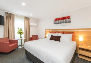 
a hotel room with a bed, chair, and nightstand at Adelaide Royal Coach in Adelaide

