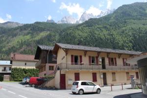 een witte auto geparkeerd voor een gebouw met bergen bij Apartment La Maisonnee in Chamonix-Mont-Blanc