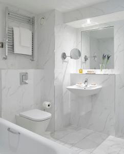 La salle de bains blanche est pourvue de toilettes et d'un lavabo. dans l'établissement Newpark Hotel, à Kilkenny