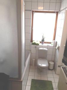 een badkamer met een toilet, een raam en een bad bij Ferienwohnung im Rhein-Main Gebiet nahe Frankfurt, Rödermark in Rödermark