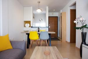 een keuken en een woonkamer met een tafel en gele stoelen bij Alhama Golf Penthouses P02 in El Romero