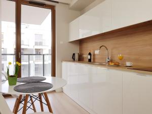 ワルシャワにあるChopin Apartments - Unionの白いキャビネット、テーブルと椅子付きのキッチンが備わります。