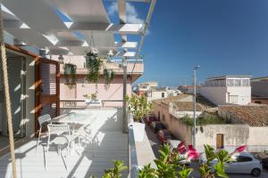 balkon ze stołem i krzesłami na budynku w obiekcie A'NACA HOLIDAY HOME w mieście Marina di Ragusa