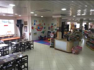 a restaurant with tables and chairs and a store at Hotel Peroza Corbelia in Corbélia