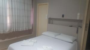 a white bed in a room with a window at Hotel Peroza Corbelia in Corbélia +37 photos