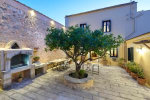 un patio con un árbol, una mesa y sillas en Castello Villa Daphnes - Private Pool & Whirlpool, en Dhafnés