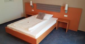 a bedroom with a large bed with an orange headboard at Frühstückspension Winter in Gössendorf