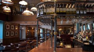 a bar with wooden tables and wine glasses at West Highland Apartments Milngavie - The Lomond in Milngavie