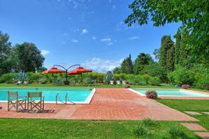 een zwembad met 2 stoelen en een parasol bij Villa Lorenza by PosarelliVillas in Bucciano