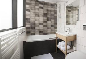 ein Badezimmer mit einer Badewanne, einem Waschbecken und einem Spiegel in der Unterkunft Hotel Izzy in Issy-les-Moulineaux