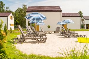 a group of chairs and umbrellas on a beach at Domki Lawendowe in Łeba