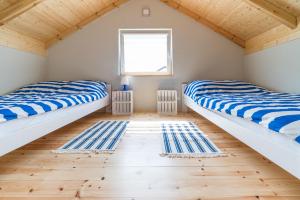 two beds in a room with wooden floors and a window at Domki Lawendowe in Łeba +45 photos