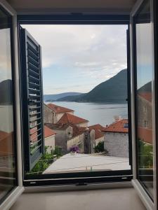 a window with a view of the water and buildings at Gudelj Apartments in Perast