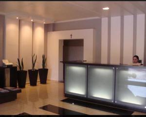 a woman sitting at a counter in a lobby at Hotel Peroza Corbelia in Corbélia