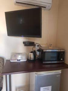 a microwave sitting on a table with a tv at Kgosi Lodge in Kimberley