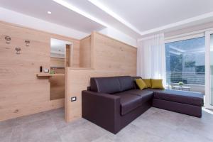 a living room with a leather couch and a window at Bellavista - Lake in Molveno