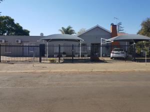 a black fence with umbrellas in front of a house at Kgosi Lodge in Kimberley