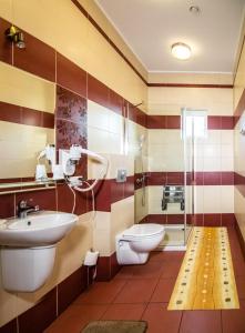 La salle de bains est pourvue d'un lavabo, de toilettes et d'une douche. dans l'établissement Hotel Platinum Hrubieszów, à Hrubieszów