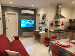 a living room with a red couch and a kitchen at Marsascala Sea View Apartment & Penthouse in Marsaskala