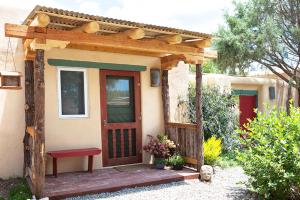 une petite maison avec une porte en bois et un banc dans l'établissement Casa Gallina - An Artisan Inn, à Taos