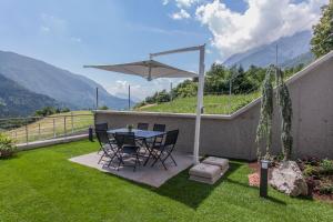a patio with a table and chairs and a umbrella at Bellavista - Lake in Molveno