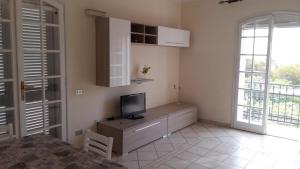 ein Wohnzimmer mit einem TV auf einem Schrank und einem Fenster in der Unterkunft Appartamento in villa in Su Forti