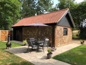 a table and chairs in front of a shed at Rivers Rest in Norwich