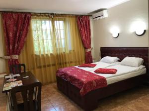 a bedroom with a bed with red sheets and a table at Felisa Hotel in Kharkiv