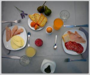Cascina Luvot في Melazzo: طاولة مع أطباق من الطعام وكؤوس من عصير البرتقال