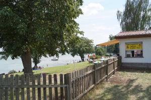 a wooden fence next to a building with a tree at Ferienwohnung Rehagen Süd in Mellensee