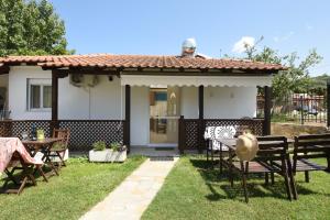 a house with a table and chairs in the yard at Haus Platanos Apartments & Bungalows by the Sea in Vourvourou