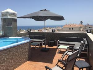 eine Terrasse mit einem Sonnenschirm und Stühlen sowie einem Pool in der Unterkunft Hostal Boutique Doña Carmen - Adults Recommended in Nerja