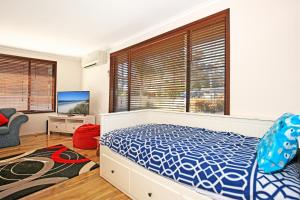 a bedroom with a bed and a large window at Sandy Toes Beach House Jervis Bay - 2min to Beach in Callala Beach