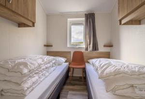 a bedroom with two beds and a chair in it at Seaside cabin Skarsvåg in Skarsvåg