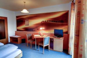 een hotelkamer met een bureau met een computer en een bed bij Hotel zum Zauberkabinett in Bad Heilbrunn