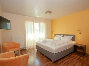 a bedroom with a large bed and a chair at Apartments Herrlichkeit Dornum in Dornum