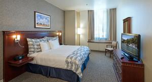ein Hotelzimmer mit einem Bett und einem Flachbild-TV in der Unterkunft Le Square Phillips Hôtel & Suites in Montreal