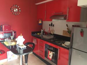 a kitchen with red cabinets and a table in it at Résidence Dreamland in Sidi Rahal