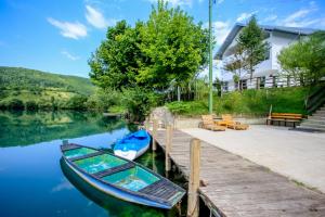 a boat sitting on the water next to a dock at Villa River Una 6 in Bihać