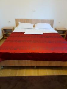 a bed with a red blanket on top of it at Casa Enka in Tuzla