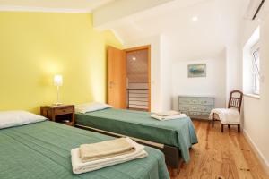 a room with two beds with green sheets at As Serenas Casa B in Vila Nova De Cacela