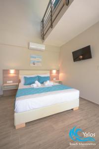 a bedroom with a large bed with blue pillows at Yalos Beach Maisonettes in Skala Sotiros