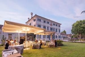grupa ludzi siedzących przy stołach przed budynkiem w obiekcie Hotel Villa Condulmer w mieście Mogliano Veneto