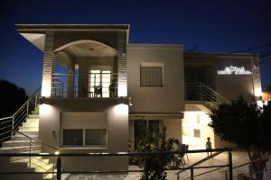 una grande casa bianca di notte con luci di Coral Boutique Apartments a Ofrínion