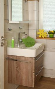 a bathroom sink with a green towel on it at Ferienhäuser May in Weigenheim