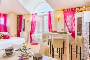 a bedroom with pink curtains and a table and chairs at Apartments Lucie in Premantura